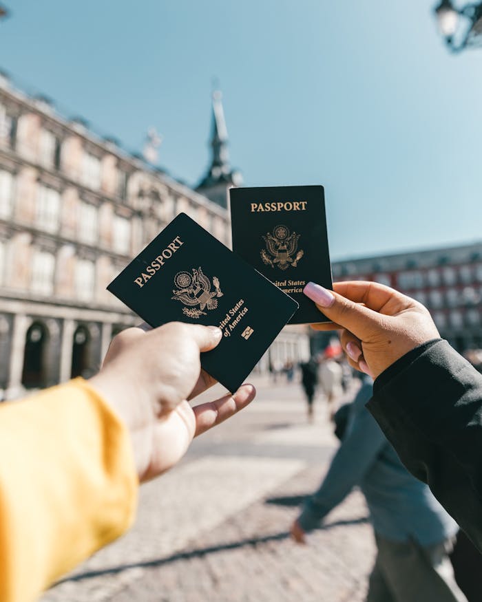 about-01 Crop unrecognizable travelers in casual clothes demonstrating passports of United States of America standing on square in historical city district